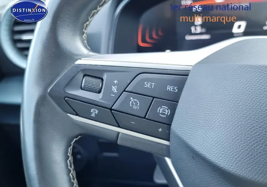 Gros plan sur les commandes du volant cuir multifonction du SEAT Arona blanc, tableau de bord numérique en arrière-plan.