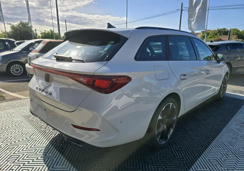 Vue 3/4 arrière droite d'une CUPRA Leon Sportstourer blanche Nevada avec feux arrière LED et jantes alliage 18 pouces.