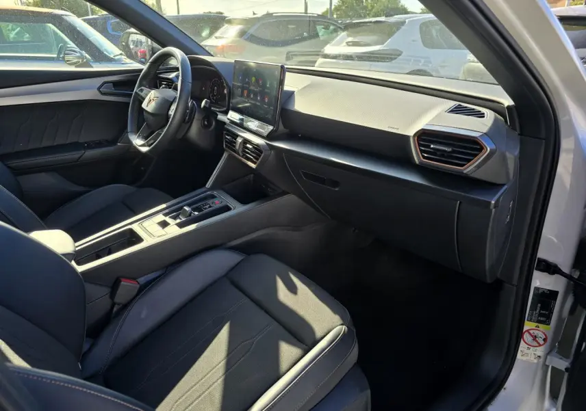 Intérieur de la CUPRA Leon Sportstourer blanc Nevada, vue côté conducteur avec tableau de bord digital et écran tactile central.