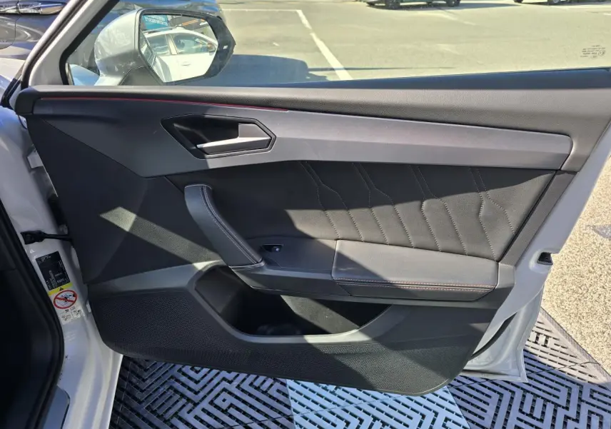 Intérieur de la porte avant gauche d'une CUPRA Leon Sportstourer blanc Nevada, avec garniture noire et surpiqûres contrastées.