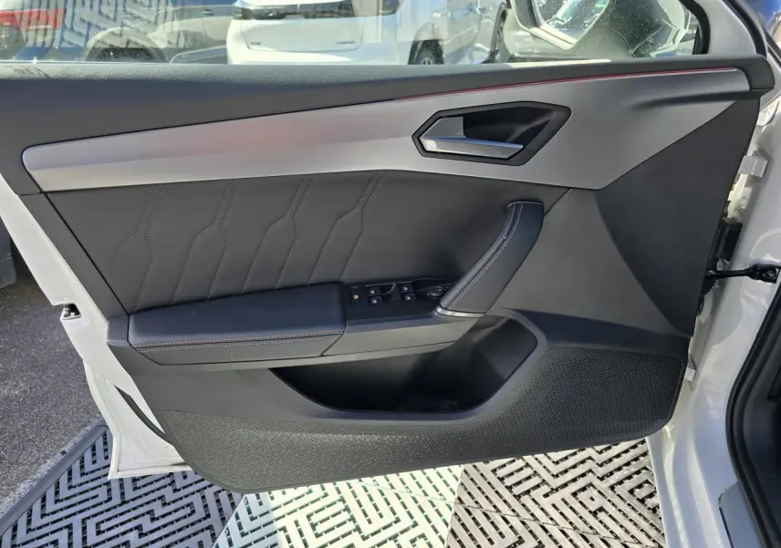 Vue rapprochée de la porte avant gauche blanche Nevada du CUPRA Leon Sportstourer avec garniture noire et surpiqûres contrastées.