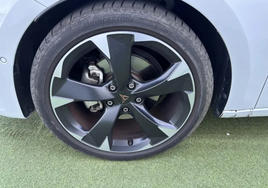 Gros plan sur la jante avant droite noire et argentée avec logo CUPRA sur une carrosserie blanc Nevada.