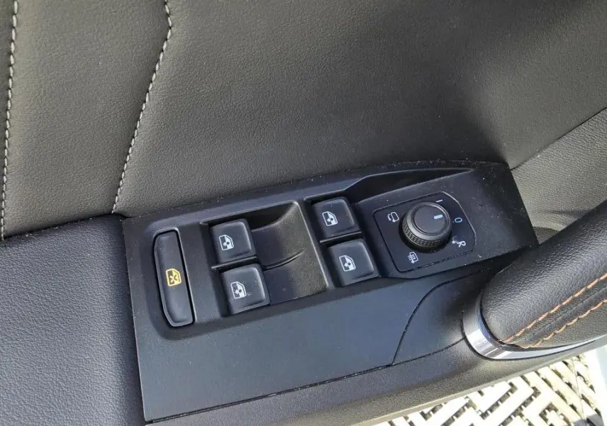 Gros plan sur les commandes des vitres et des rétroviseurs côté conducteur d'une CUPRA Leon Sportstourer 2024 en cuir noir.