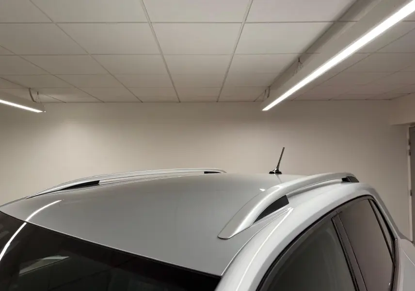 Vue en plongée du toit argent métallisé du Volkswagen T-Cross 1.5 TSI 150 DSG7 R-Line avec barres de toit et antenne.