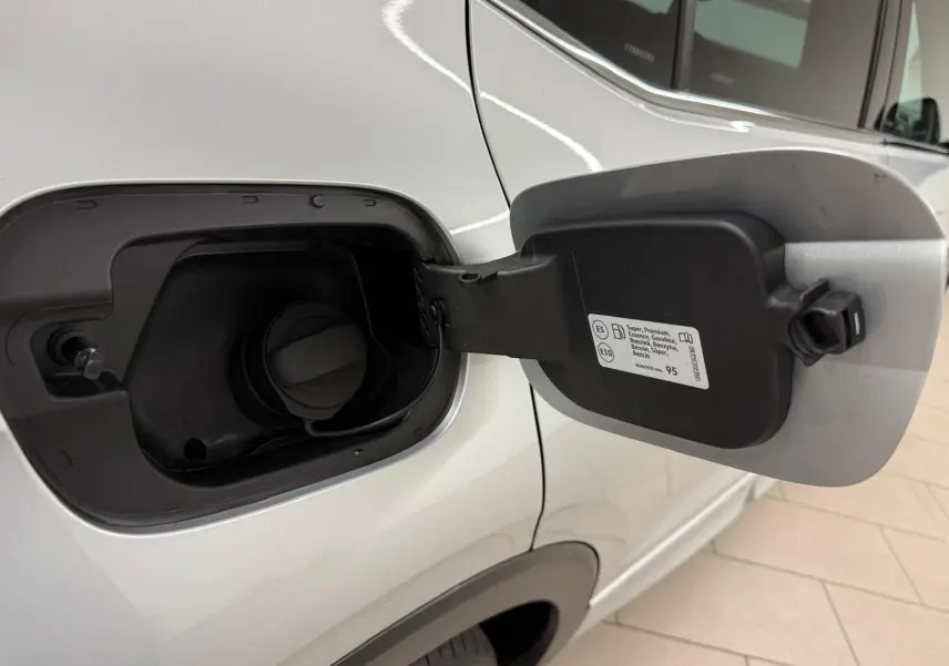 Gros plan sur la trappe à carburant côté gauche d’un Volkswagen T-Cross 1.5 TSI 150 DSG7 R-Line argent reflet d'argent.