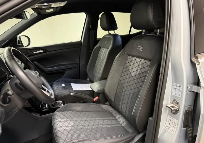 Vue intérieure côté conducteur du Volkswagen T-Cross 1.5 TSI R-Line 2024, sièges avant noirs avec surpiqûres et logo R-Line.