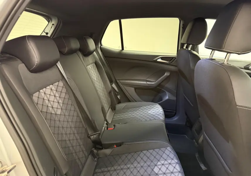 Vue intérieure côté droit de la banquette arrière du Volkswagen T-Cross 2024 avec sièges en tissu noir à motifs géométriques.