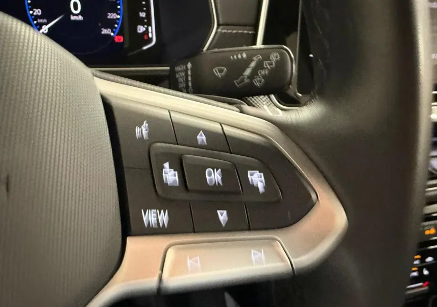 Gros plan sur les commandes multifonctions à gauche du volant du Volkswagen T-Cross 1.5 TSI 150 DSG7 R-Line 2024.