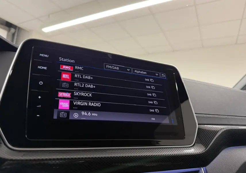 Écran tactile central du Volkswagen T-Cross 2024 affichant les stations radio FM/DAB en intérieur noir.