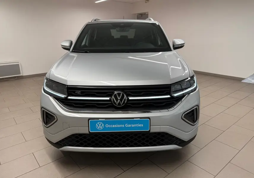 Vue frontale d'un Volkswagen T-Cross 1.5 TSI 150 DSG7 R-Line en peinture métallisée Reflet d'Argent, intérieur showroom.