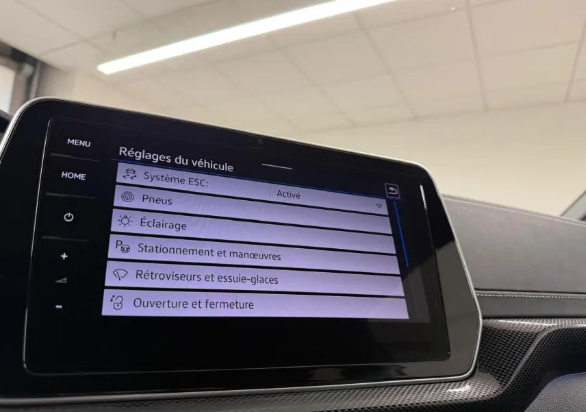 Écran tactile central du Volkswagen T-Cross 2024 affichant les réglages du véhicule, avec tableau de bord noir et inserts gris.