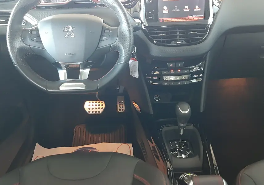 Vue intérieure du poste de conduite du Peugeot 2008 GT Line 2019 avec volant compact, écran tactile et sellerie noire avec surpiqûres rouges.