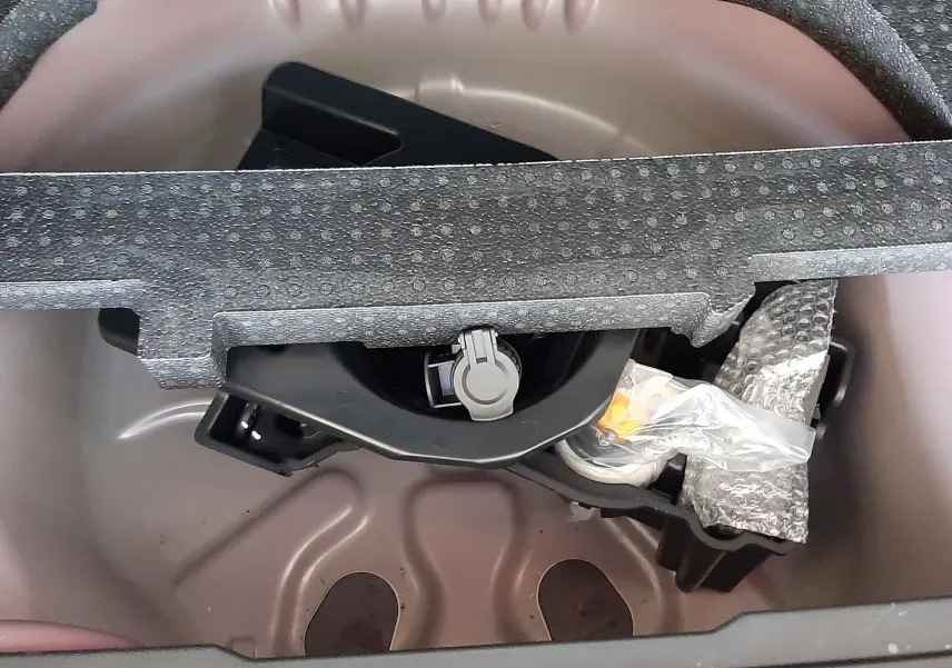 Coffre ouvert du Peugeot 2008 rouge Ultimate Metal, vue plongeante sur la roue de secours et son support en mousse grise.