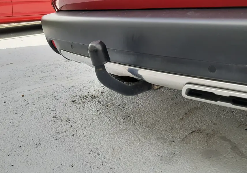 Gros plan sur l'attelage arrière noir d'un Peugeot 2008 rouge Ultimate Metal, avec pare-chocs noir et sortie d'échappement chromée.