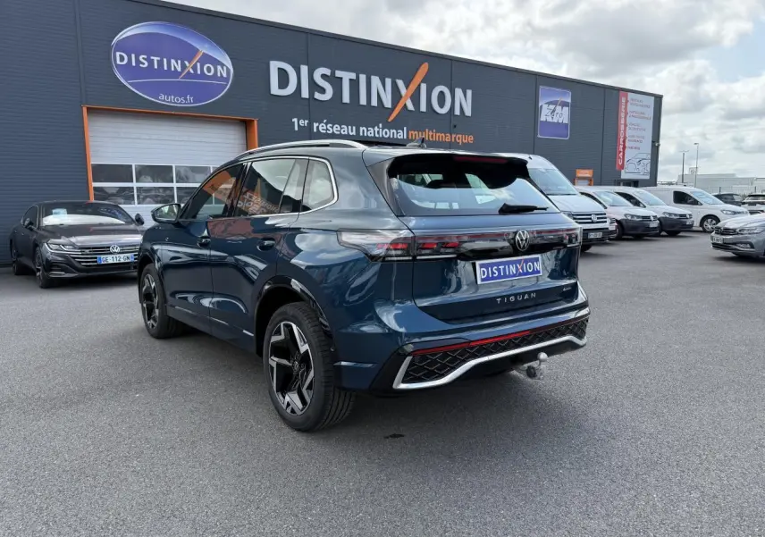Volkswagen Tiguan 2024 bleu Nightshade vu 3/4 arrière droit avec crochet d'attelage et jantes R-Line noires.