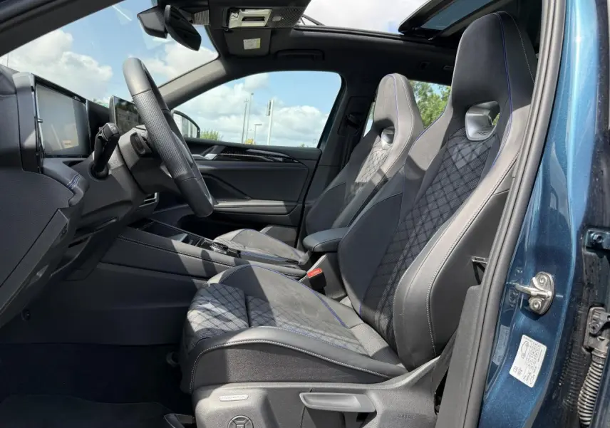 Intérieur côté conducteur du Volkswagen Tiguan 2024 bleu Nightshade, sièges sport R-Line en cuir et alcantara avec surpiqûres bleues.