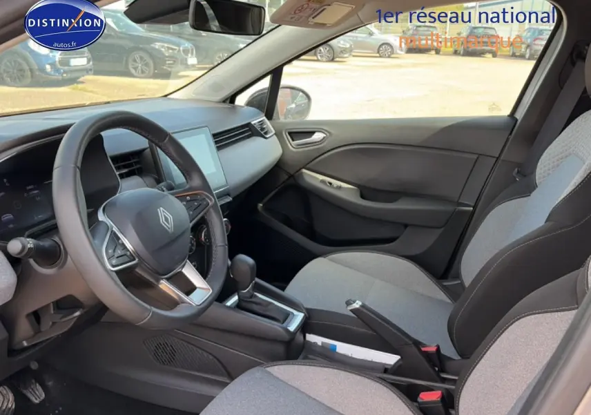 Intérieur de Renault Clio V gris foncé, vue côté conducteur, volant multifonction et sièges tissu gris à motifs 3D.