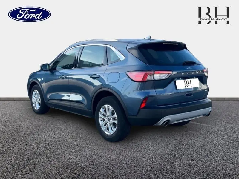 Vue 3/4 arrière droite du Ford Kuga 2023 bleu azur métallisé avec jantes alu et double sortie d’échappement.