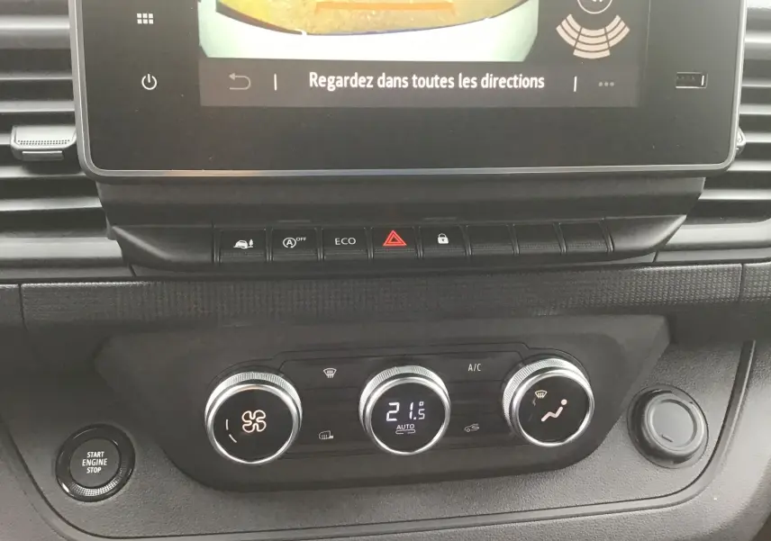 Gros plan sur la console centrale du Renault Trafic blanc, montrant les commandes de climatisation et l'écran tactile avec caméra de recul.