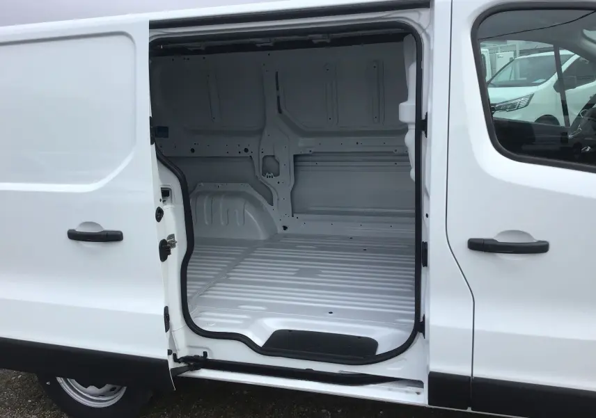 Vue latérale droite d’un Renault Trafic Fourgon blanc 2025 avec porte coulissante ouverte montrant l’espace de chargement vide.