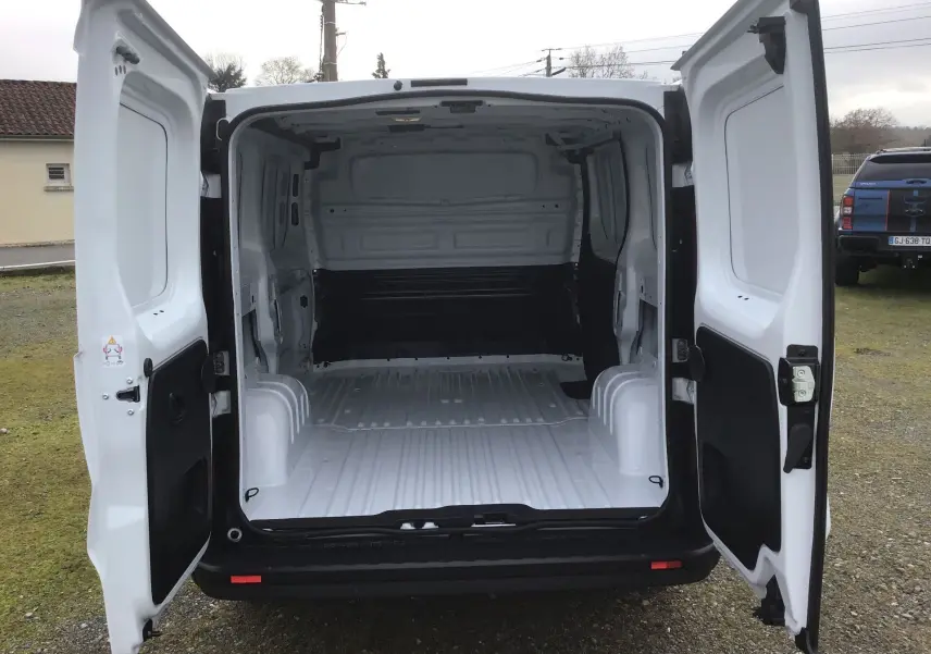 Vue arrière du Renault Trafic Fourgon blanc 2025 avec portes ouvertes montrant l'espace de chargement vide.