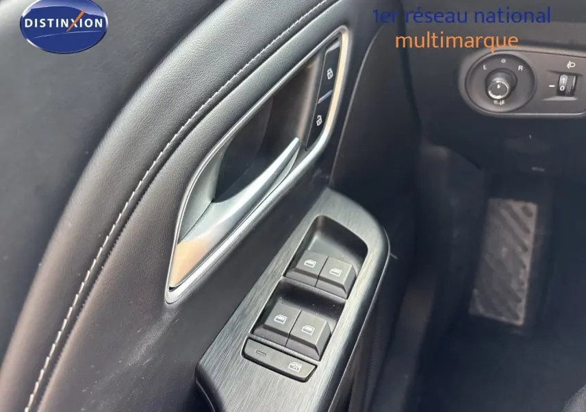 Gros plan sur la porte côté conducteur du MG ZS 2025 en Pebble Black, avec commandes de vitres et poignée argentée.