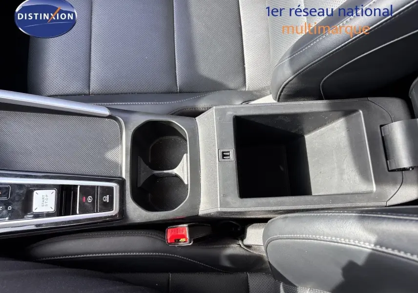 Vue plongeante sur la console centrale noire en cuir perforé du MG ZS 1.5L Hybrid+ 197ch Luxury avec porte-gobelets et rangement ouvert.