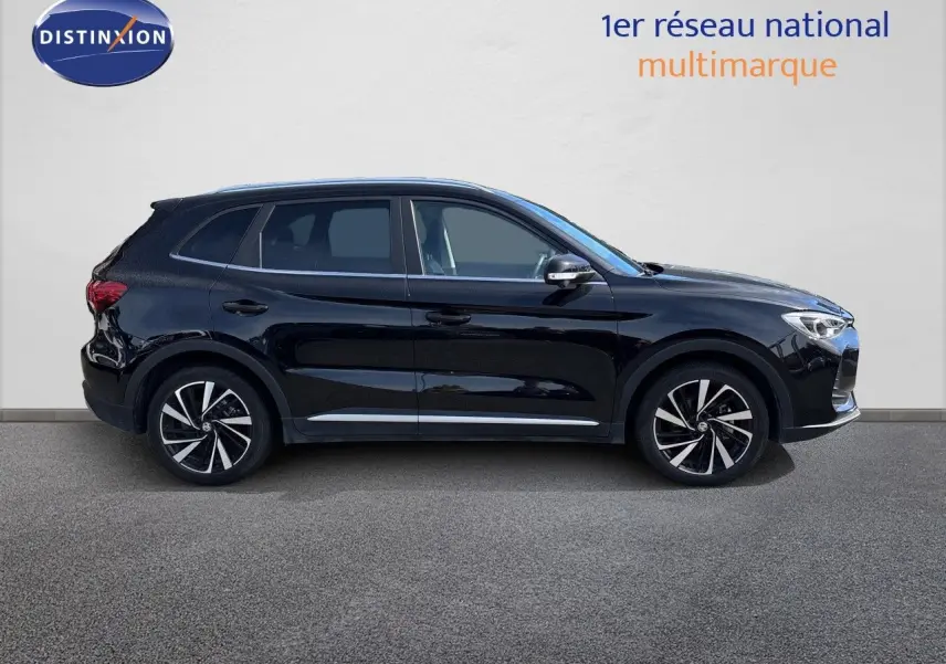 Vue de profil côté gauche du MG MOTOR ZS 1.5L HYBRID+ 197CH LUXURY en noir Pebble Black Metal avec jantes bi-ton.