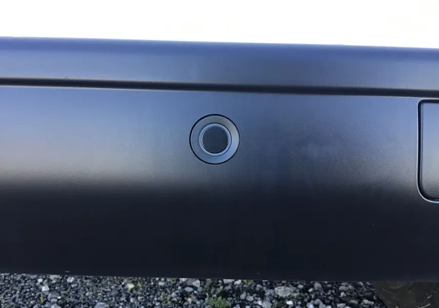 Gros plan sur le capteur de recul noir intégré au pare-chocs arrière du Peugeot Expert Fourgon blanc 2024.