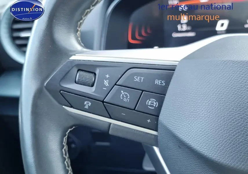 Gros plan sur les commandes de régulateur de vitesse au volant cuir du SEAT Arona blanc 2023.