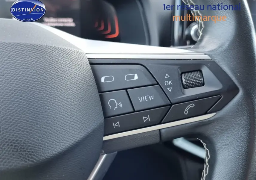 Gros plan sur les commandes multifonctions du volant cuir noir du SEAT Arona blanc 2023, côté droit.