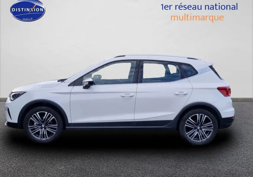 Profil côté gauche d'un SUV SEAT Arona blanc 2023 avec jantes alliage et barres de toit noires.