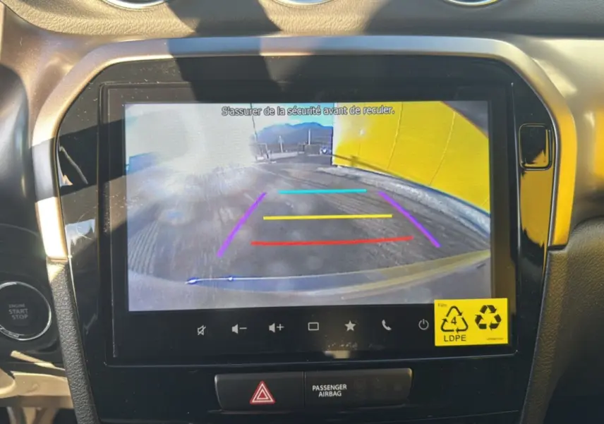 Écran central du Suzuki Vitara 2025 montrant la caméra de recul avec repères colorés dans un intérieur noir et gris.