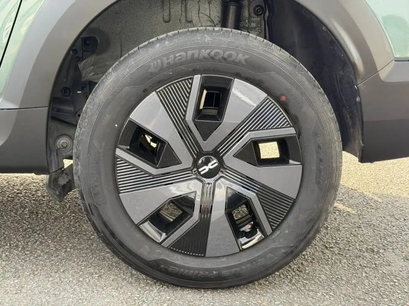 Gros plan sur la roue avant gauche du Dacia Jogger 2025 vert cèdre métallisé avec jante au design moderne noir et gris.