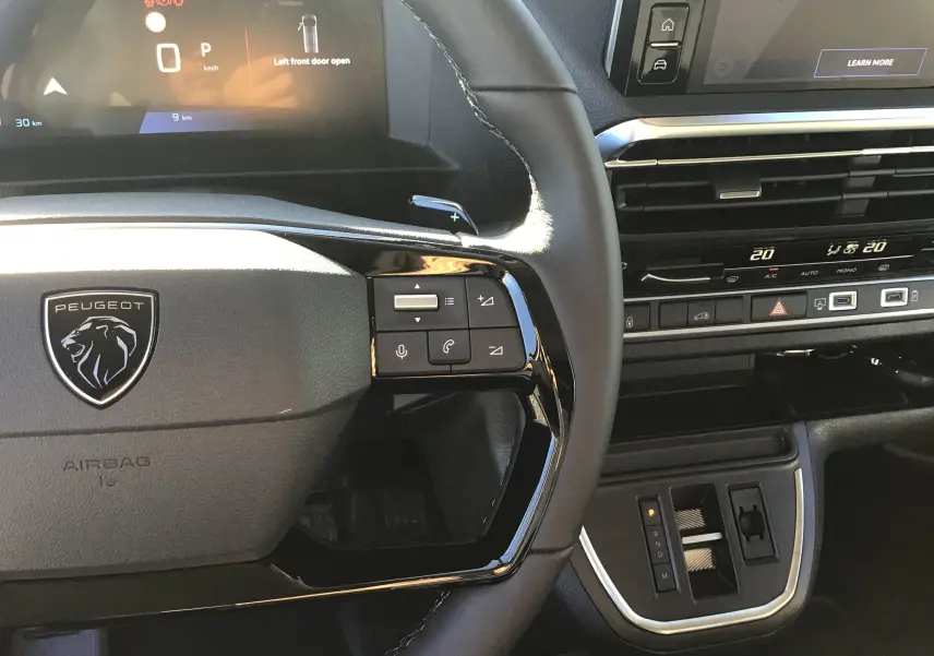 Vue rapprochée du volant noir et du tableau de bord moderne du Peugeot Expert Fourgon blanc 2024 avec commandes intégrées.