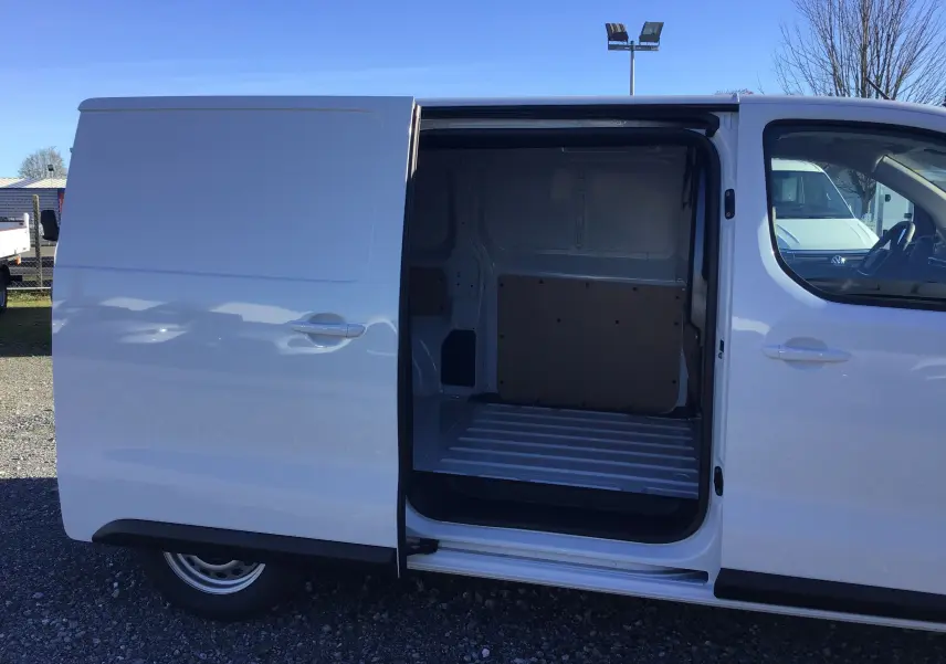 Vue latérale droite du Peugeot Expert Fourgon blanc 2024 avec porte coulissante ouverte dévoilant l'espace de chargement vide.