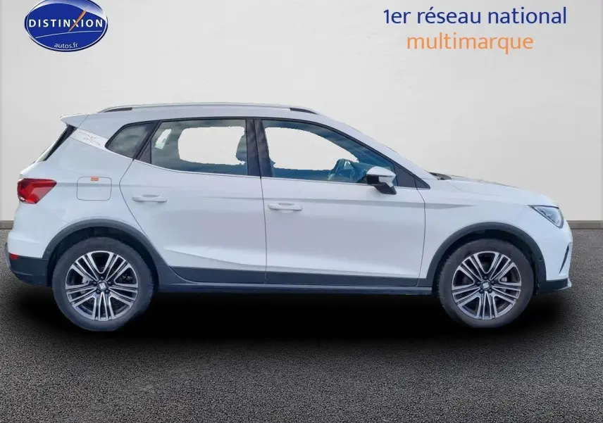 Profil côté gauche d'un SUV SEAT Arona blanc 2023 avec jantes alu 17 pouces et barres de toit noires.