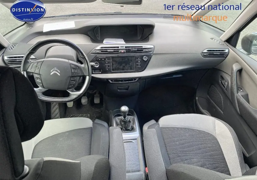 Intérieur avant de la Citroën C4 Picasso gris 2016, volant multifonction et boîte manuelle visibles, sièges tissu bicolore.