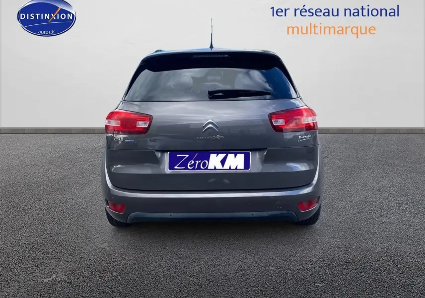 Vue arrière d'une Citroën C4 Picasso gris métallisé avec feux rouges et plaque Zéro KM visible.