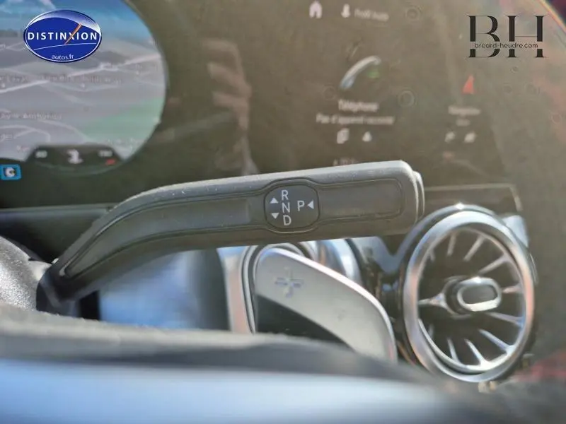 Gros plan sur la commande de boîte automatique et la sortie d'air ronde à turbine dans l'habitacle d'un Mercedes GLB blanc polaire.