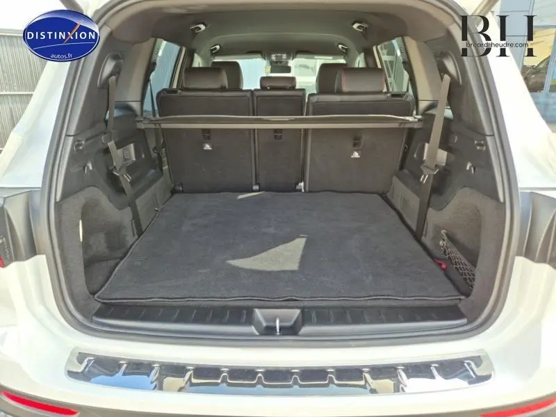 Coffre ouvert d’un Mercedes GLB blanc polaire 2023, montrant la 3ème rangée de sièges et un tapis noir.