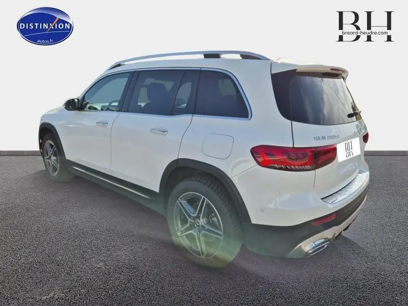 Vue 3/4 arrière droite d'un Mercedes GLB 200 d blanc polaire avec jantes AMG et vitres arrière surteintées.