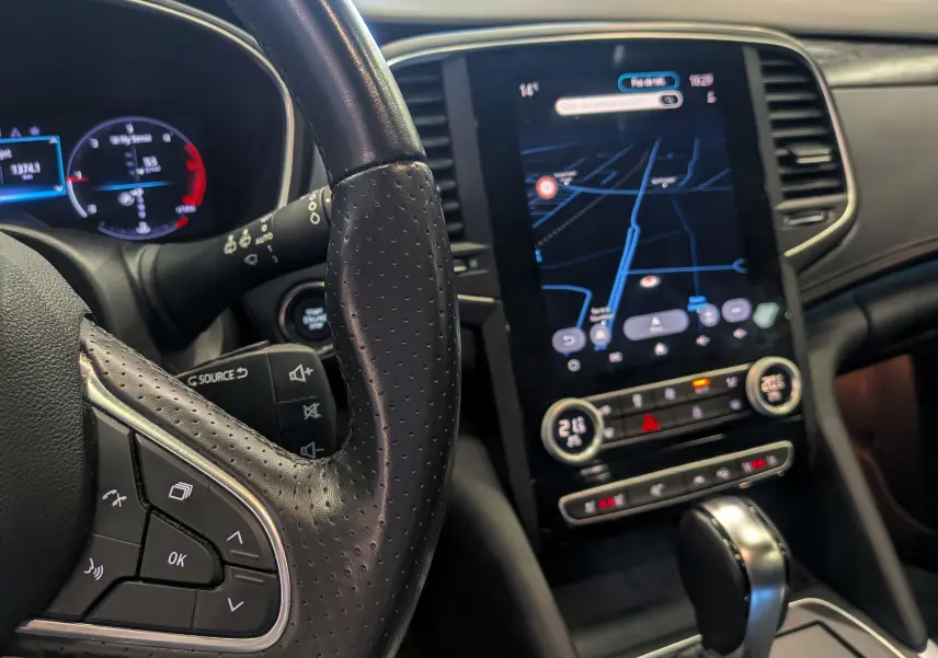 Gros plan sur le volant en cuir perforé et l'écran tactile central affichant la navigation dans une Renault Talisman Estate gris Cassiopé.