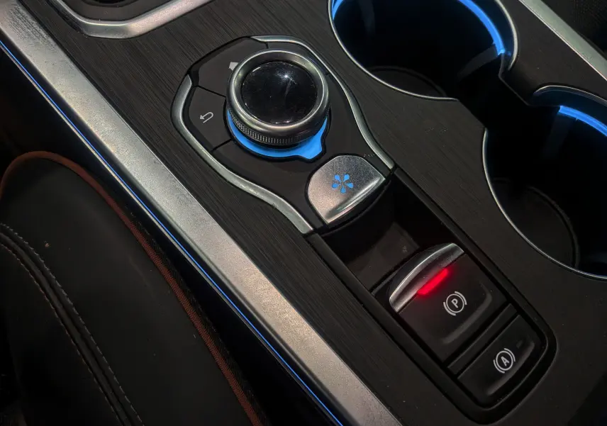 Gros plan sur la console centrale du Renault Talisman Estate 2022, avec molette de commande et frein à main électronique allumé.