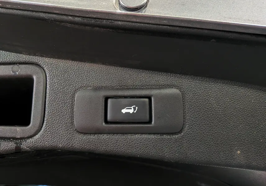 Bouton noir de commande d'ouverture électrique du hayon sur le coffre d'une Renault Talisman Estate gris Cassiopé.