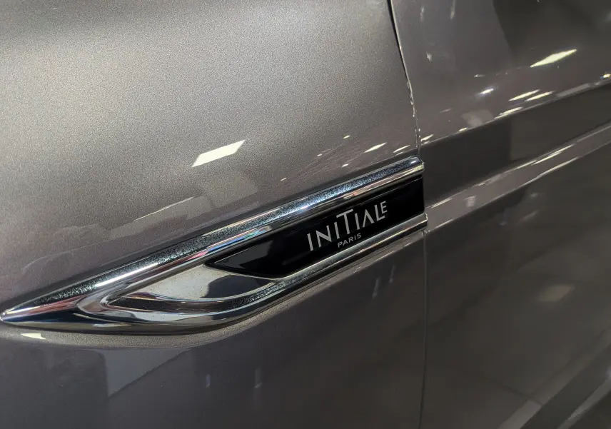 Gros plan sur l'emblème Initiale Paris sur la porte côté droit d'une Renault Talisman Estate gris Cassiopé.