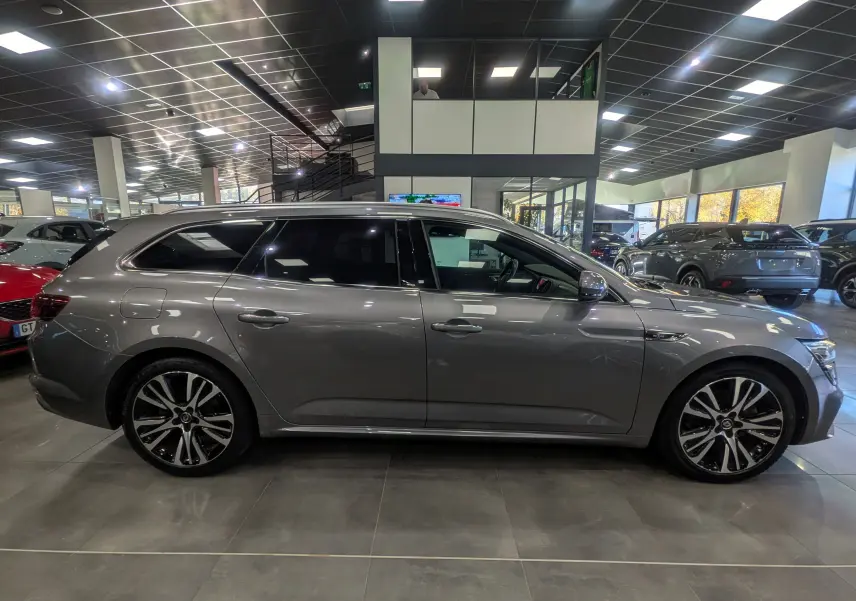 Profil côté gauche d'une Renault Talisman Estate gris Cassiopé 2022 en showroom, avec jantes alliage bicolores.