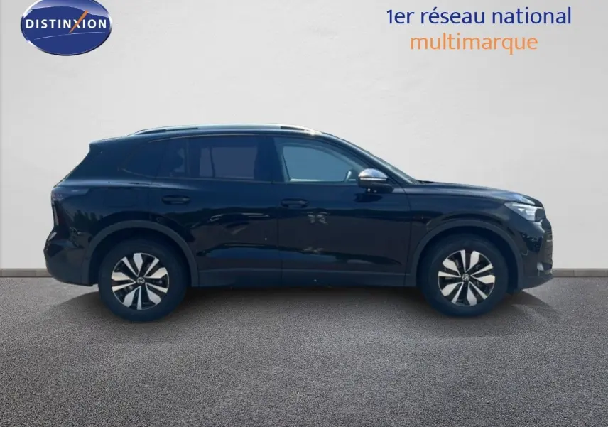 Vue de profil côté gauche d'un Volkswagen Tiguan noir métallisé, avec jantes distinctives et lignes épurées.
