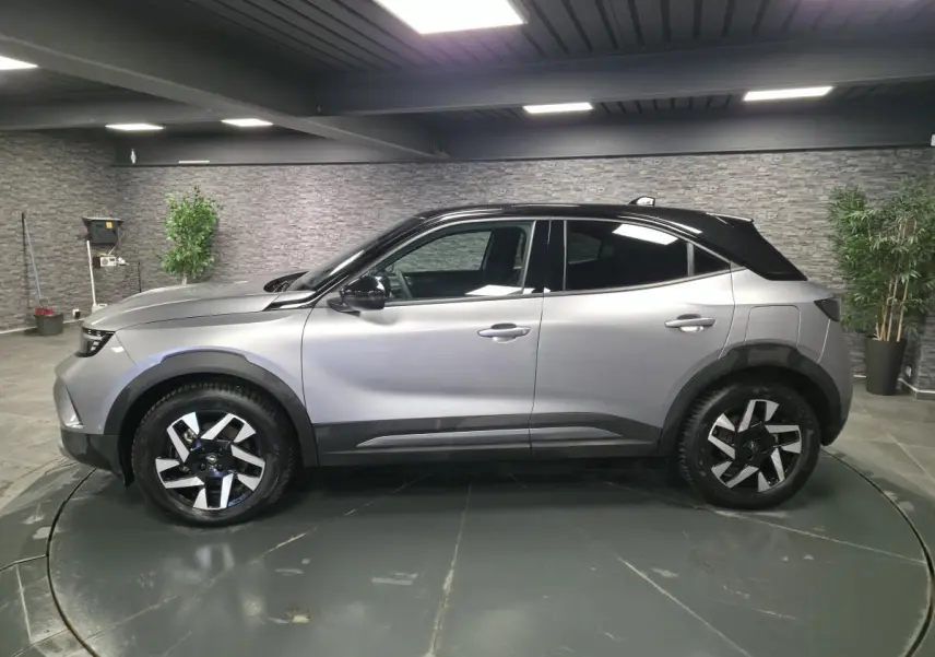 Opel Mokka-e 2025 gris avec toit noir, vue de profil côté gauche, jantes alliage diamantées 17 pouces.