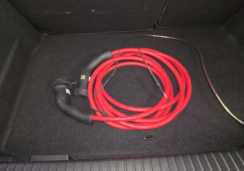 Câble de recharge rouge enroulé dans le coffre noir d'un Opel Mokka-e gris, vue intérieure arrière.
